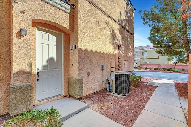 entrance to property with central AC unit and stucco siding