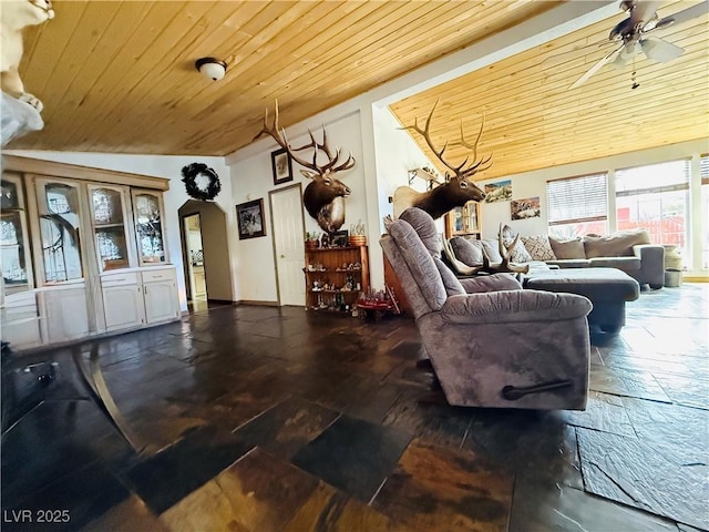 living area featuring arched walkways, a ceiling fan, and wooden ceiling