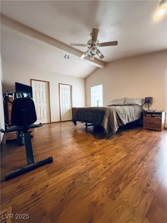 bedroom with a ceiling fan, lofted ceiling with beams, wood finished floors, and multiple closets