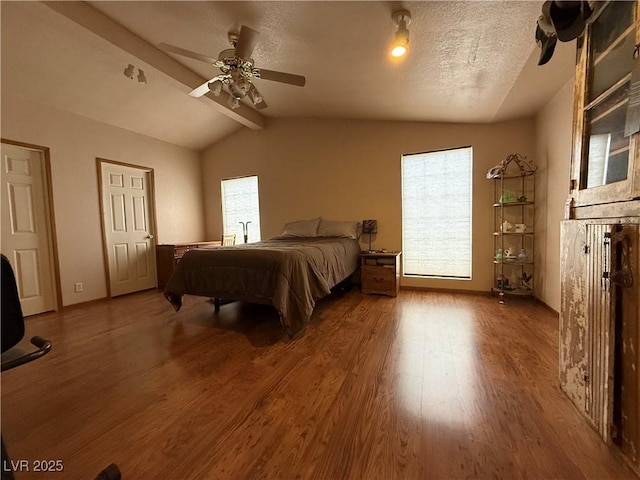 bedroom featuring lofted ceiling with beams, wood finished floors, ceiling fan, and a textured ceiling