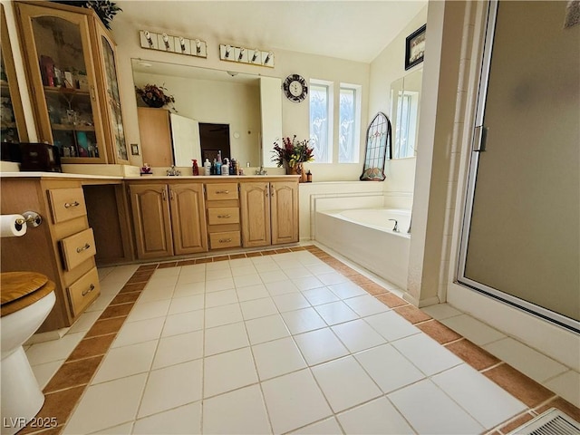 bathroom featuring double vanity, a sink, a stall shower, a garden tub, and tile patterned flooring