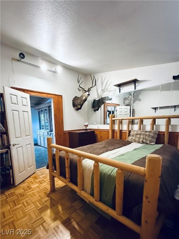 bedroom with wainscoting, wood walls, and a textured ceiling