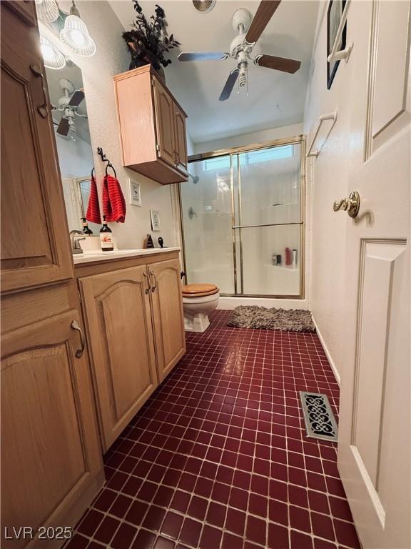 full bath featuring a shower with door, toilet, ceiling fan, and vanity