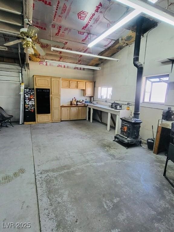 garage with a workshop area, a wood stove, and a ceiling fan