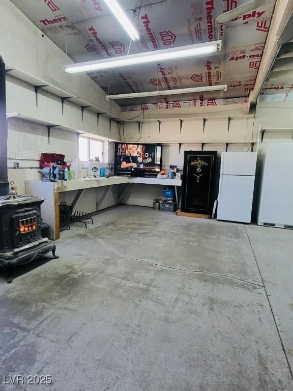 garage featuring a wood stove and freestanding refrigerator