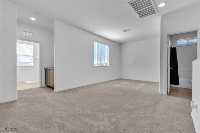 spare room with visible vents, a healthy amount of sunlight, and light colored carpet