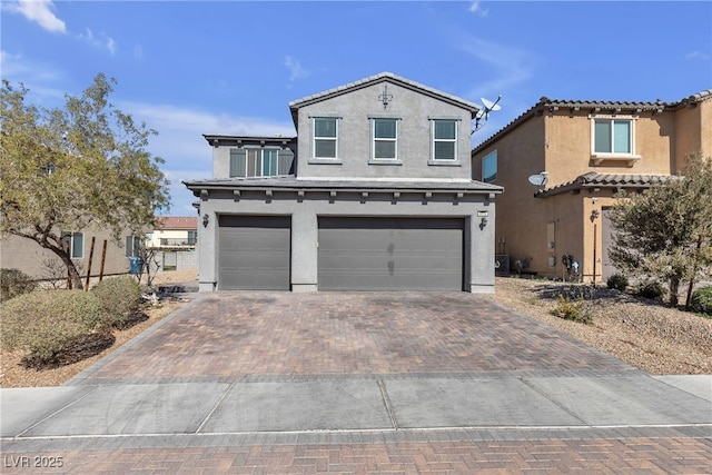 view of front facade with stucco siding, a tiled roof, decorative driveway, and a garage