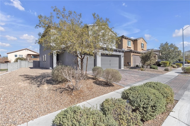 view of front of home with decorative driveway, fence, a garage, and stucco siding