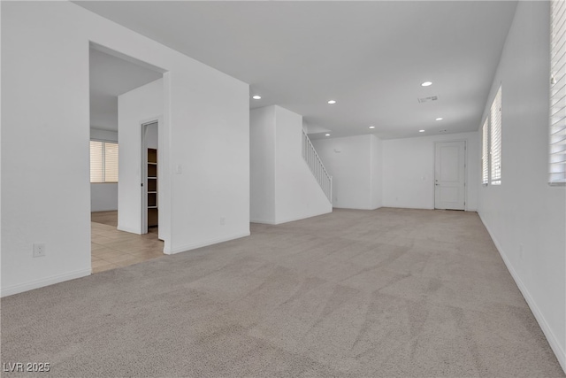 empty room featuring stairs, recessed lighting, baseboards, and light carpet