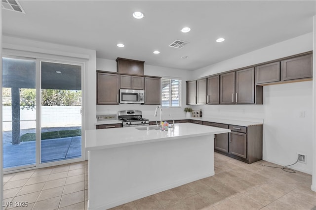 kitchen with dark brown cabinetry, visible vents, stainless steel appliances, and a sink