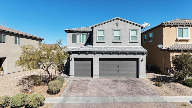 view of front of house with stucco siding, a tiled roof, decorative driveway, and a garage