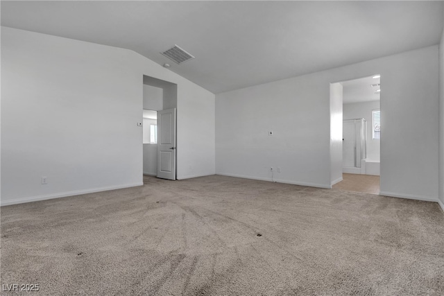 carpeted empty room with visible vents, lofted ceiling, and baseboards