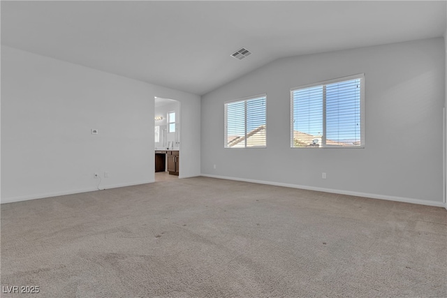 empty room with visible vents, light carpet, baseboards, and vaulted ceiling