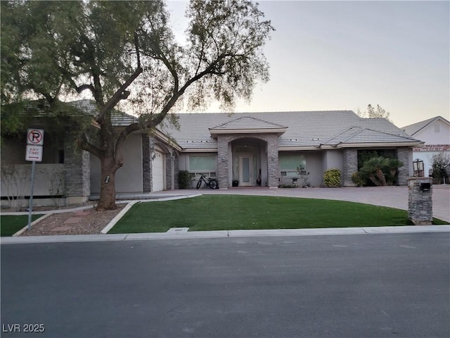 view of front of home with a front yard, stone siding, driveway, and an attached garage