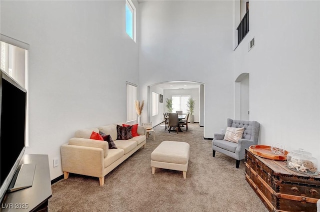 carpeted living room with visible vents and arched walkways