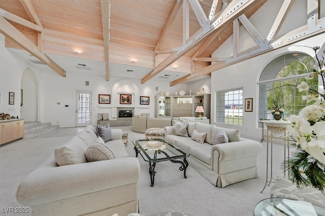 living room with high vaulted ceiling, a glass covered fireplace, beamed ceiling, and arched walkways