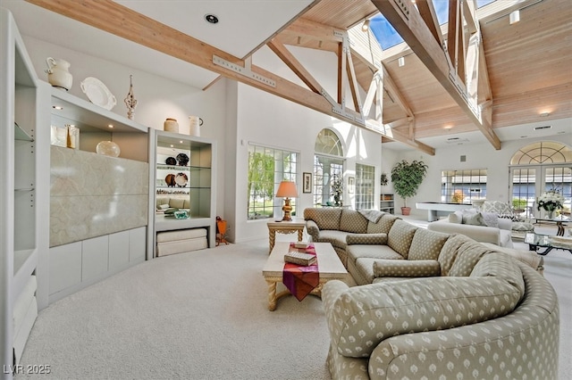 carpeted living room featuring wooden ceiling, a skylight, high vaulted ceiling, and beam ceiling