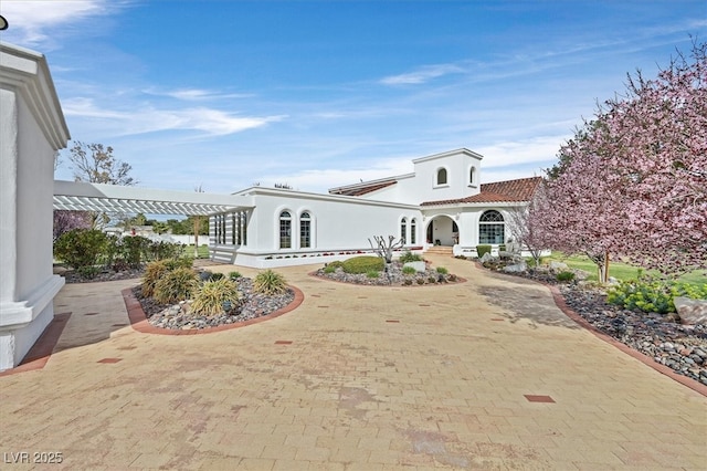 view of front of home with decorative driveway, a tile roof, and stucco siding