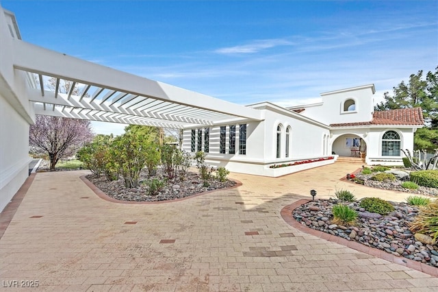 exterior space with a tile roof, a pergola, and stucco siding