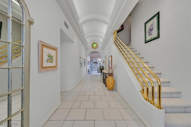 tiled foyer entrance with arched walkways, stairway, visible vents, and baseboards