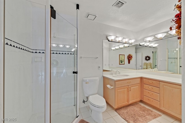 bathroom with tile patterned flooring, toilet, vanity, visible vents, and a stall shower