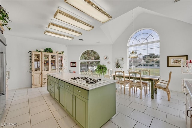 kitchen featuring green cabinets, a center island, vaulted ceiling, white gas cooktop, and light tile patterned flooring