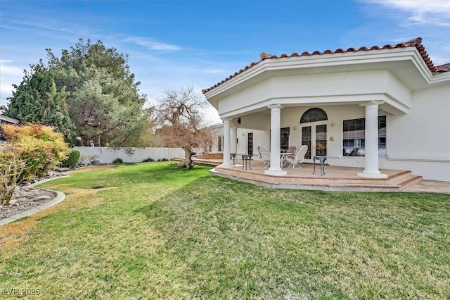 rear view of property with a lawn, fence, and stucco siding