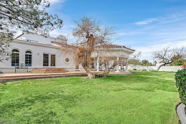 rear view of house with a yard, stucco siding, and french doors