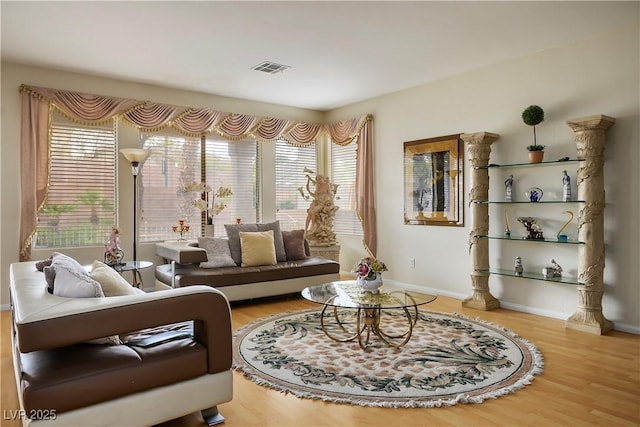 living room with visible vents, baseboards, and wood finished floors