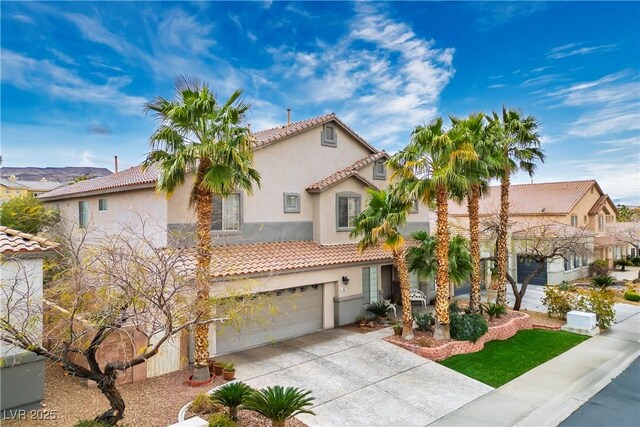 mediterranean / spanish home with a garage, a tiled roof, concrete driveway, and stucco siding