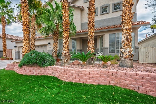 mediterranean / spanish home featuring a front yard, driveway, an attached garage, and stucco siding