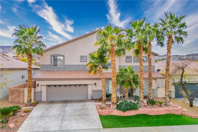 mediterranean / spanish home with a garage, a tile roof, driveway, and stucco siding