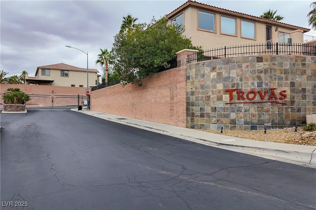 view of road with street lighting, a gated entry, curbs, a gate, and sidewalks