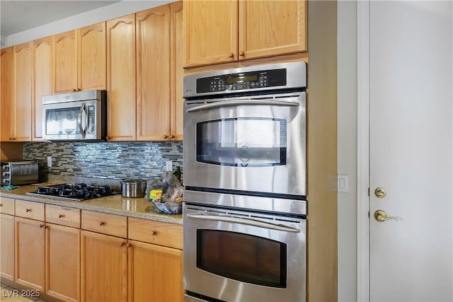 kitchen with light stone counters, a toaster, tasteful backsplash, appliances with stainless steel finishes, and light brown cabinets