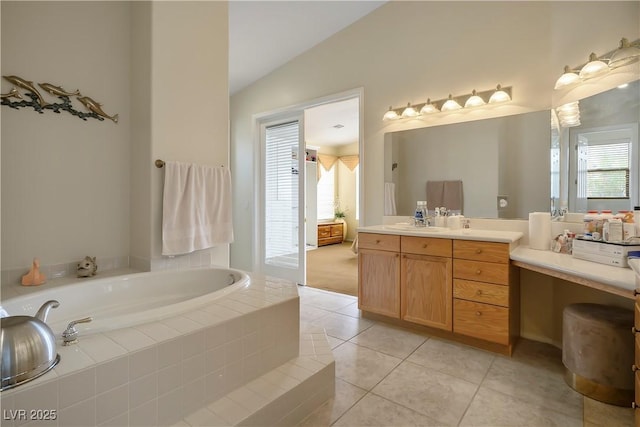 bathroom featuring plenty of natural light, tile patterned flooring, vaulted ceiling, vanity, and a bath