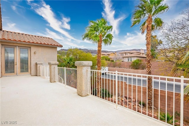 view of patio / terrace with a balcony, fence, and french doors