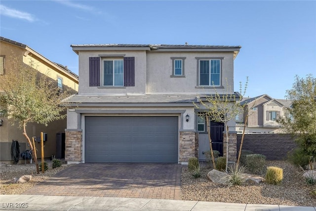 view of front of property featuring decorative driveway, stone siding, an attached garage, and stucco siding