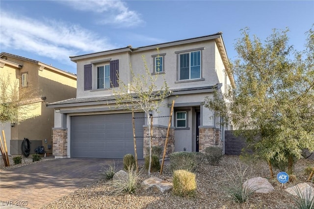 view of front facade with decorative driveway, stone siding, an attached garage, and stucco siding