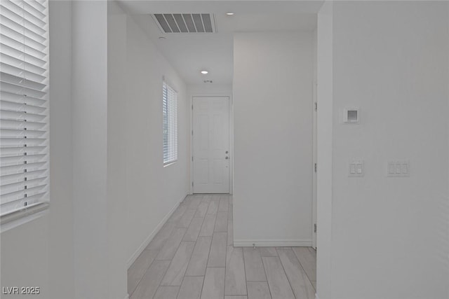 hallway featuring wood tiled floor, visible vents, baseboards, and recessed lighting