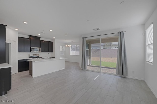 kitchen featuring visible vents, an inviting chandelier, stainless steel appliances, light countertops, and a sink