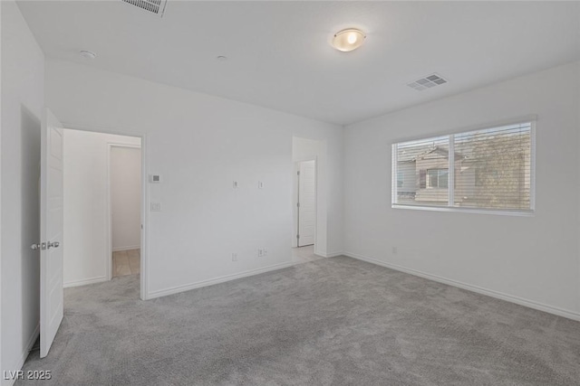 unfurnished room with carpet, visible vents, and baseboards