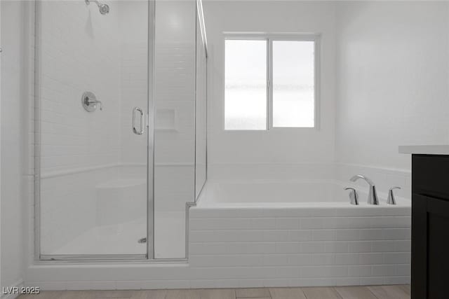 full bathroom featuring a stall shower, vanity, and a bath