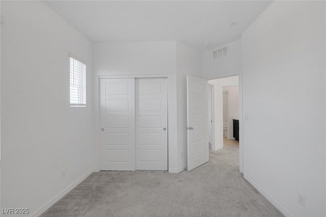 unfurnished bedroom with baseboards, visible vents, a closet, and light colored carpet