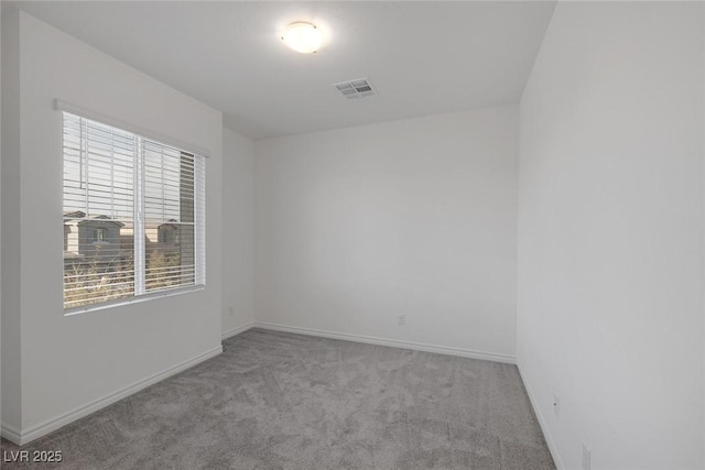 empty room featuring carpet floors, visible vents, and baseboards