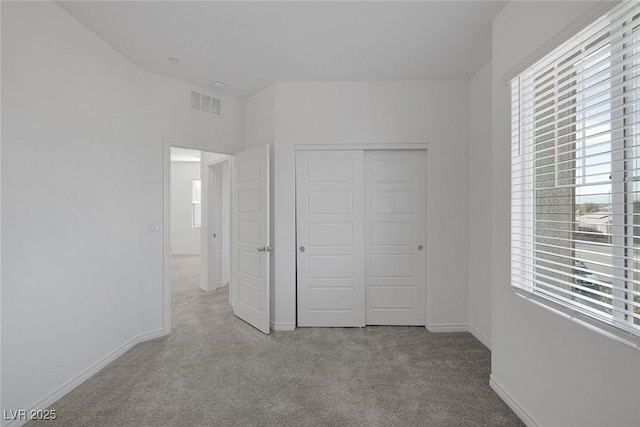 unfurnished bedroom with carpet, a closet, visible vents, and baseboards