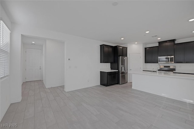 kitchen with recessed lighting, baseboards, light countertops, appliances with stainless steel finishes, and light wood finished floors