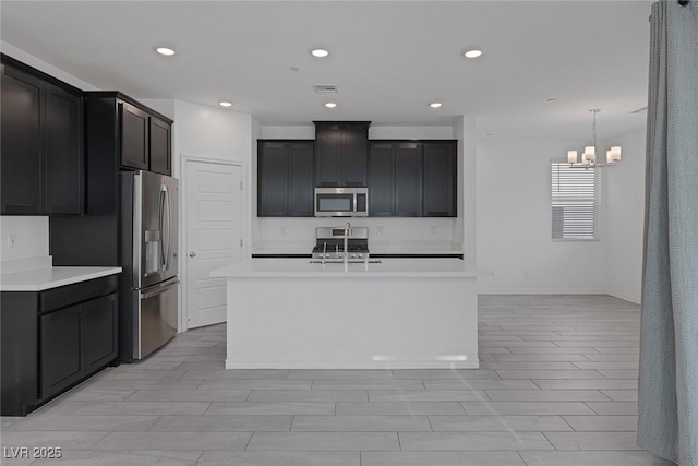 kitchen featuring a kitchen island with sink, stainless steel appliances, a sink, visible vents, and light countertops