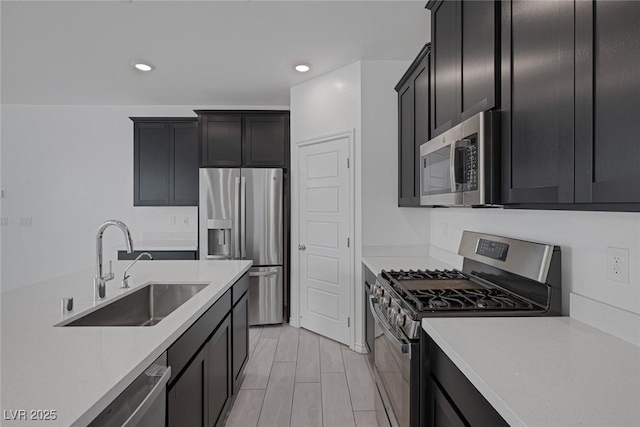 kitchen with appliances with stainless steel finishes, recessed lighting, light countertops, and a sink