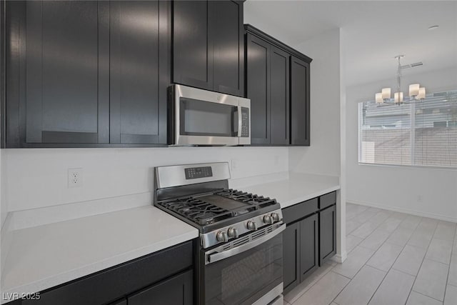 kitchen with stainless steel appliances, a chandelier, light countertops, and dark cabinetry