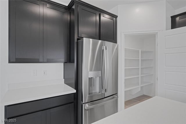 kitchen with light countertops, light wood-type flooring, and stainless steel fridge